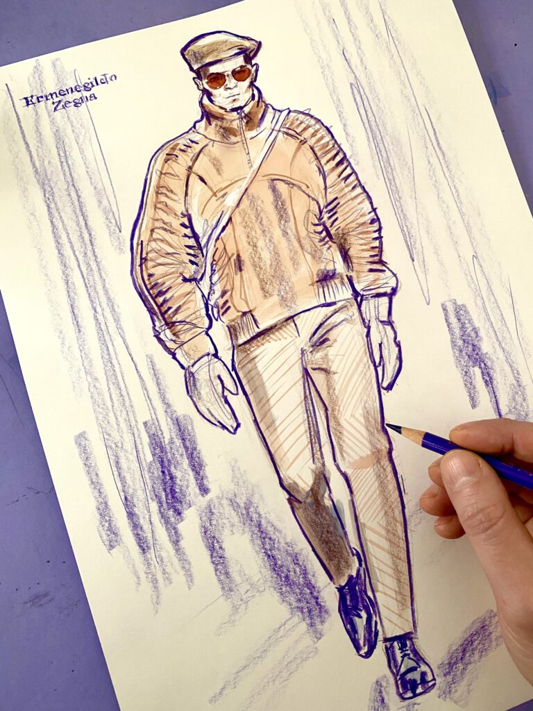 fashion illustration of a male model in a light brown suede bomber jacket a hand is drawing on it with a purple crayon 