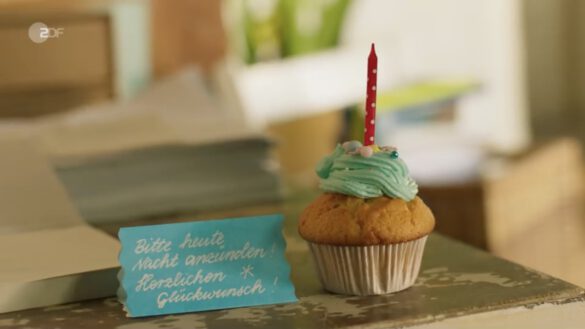 ein dekorierter Muffin mit Kerze mit einer Geburtstagsnotiz
