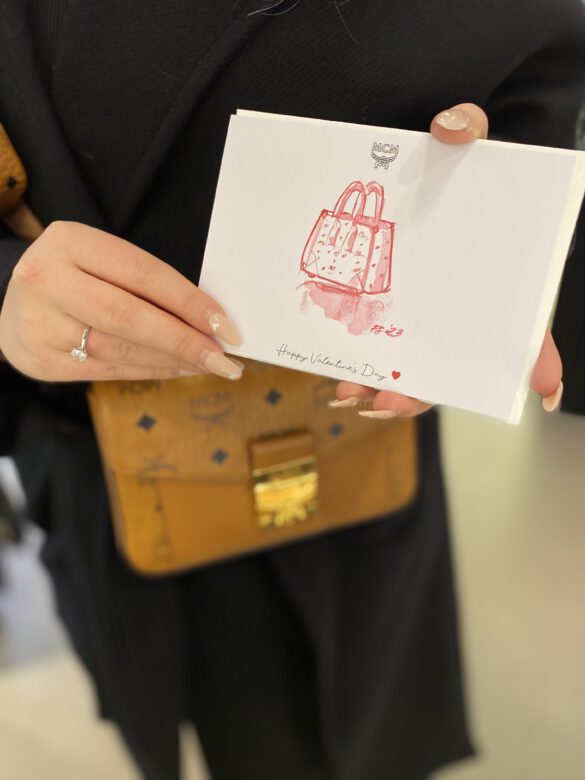 illustration einer Handtasche auf einer weissen karte gehalten von Händen