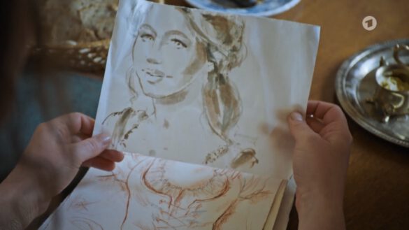 das gezeichnete portrait einer jungen Frau wird in beiden Händen gehalten