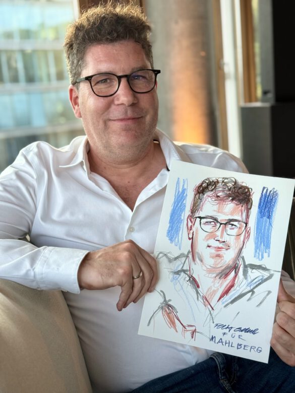 Gast mit farbiger Portraitzeichnung in der Hand beim Event von Juwelier Mahlberg