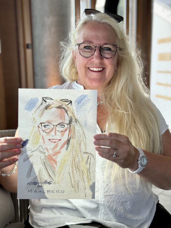 Gast mit farbiger Portraitzeichnung in der Hand beim Event von Juwelier Mahlberg