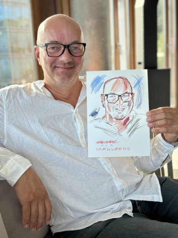 Gast mit farbiger Portraitzeichnung in der Hand beim Event von Juwelier Mahlberg