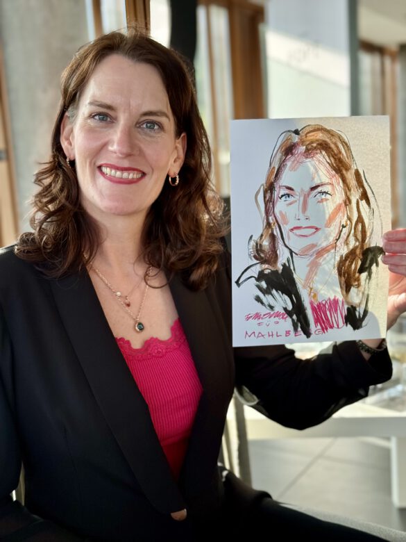 Gast mit farbiger Portraitzeichnung in der Hand beim Event von Juwelier Mahlberg