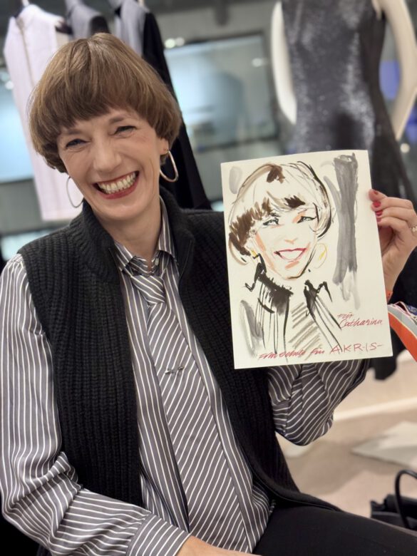 Lachende Dame beim AKRIS Dinner in Hamburg, in den Händen eine Portraitzeichnung von ihr von Felix Scholz Illustration