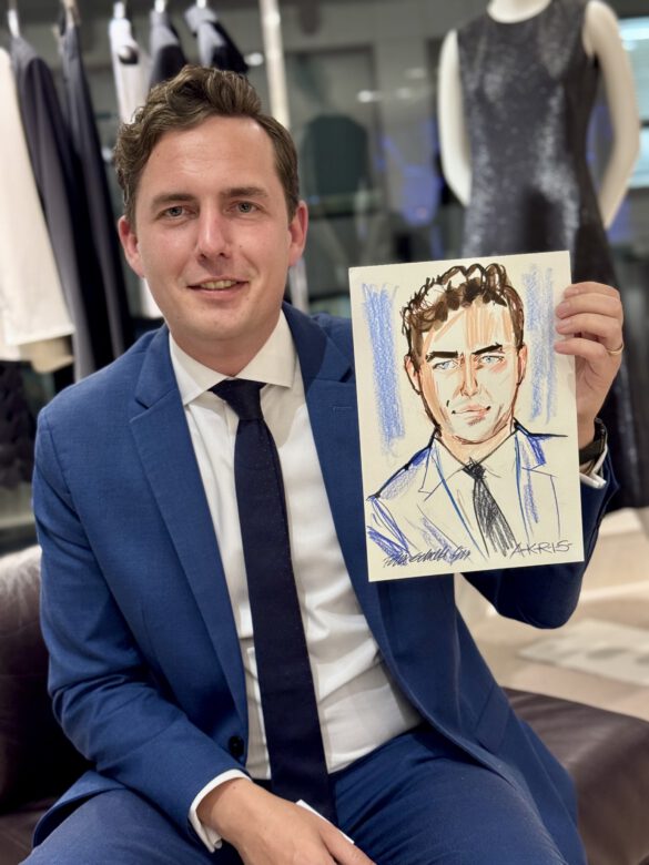 Herr im Blauen Anzug mit Krawatte beim AKRIS Dinner in Hamburg, in den Händen eine Portraitzeichnung von ihm von Felix Scholz Illustration