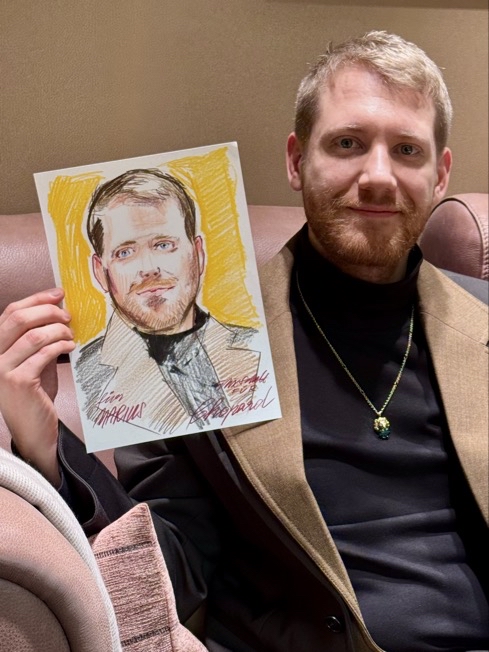 Felix Scholz_Live Event Illustration_Chopard Berlin Kurfürstendamm_15 Ein junger blonder Mann mit Bart und goldener Kette hält eine farbige Portraitzeichnung des Berliner Künstlers Felix Scholz