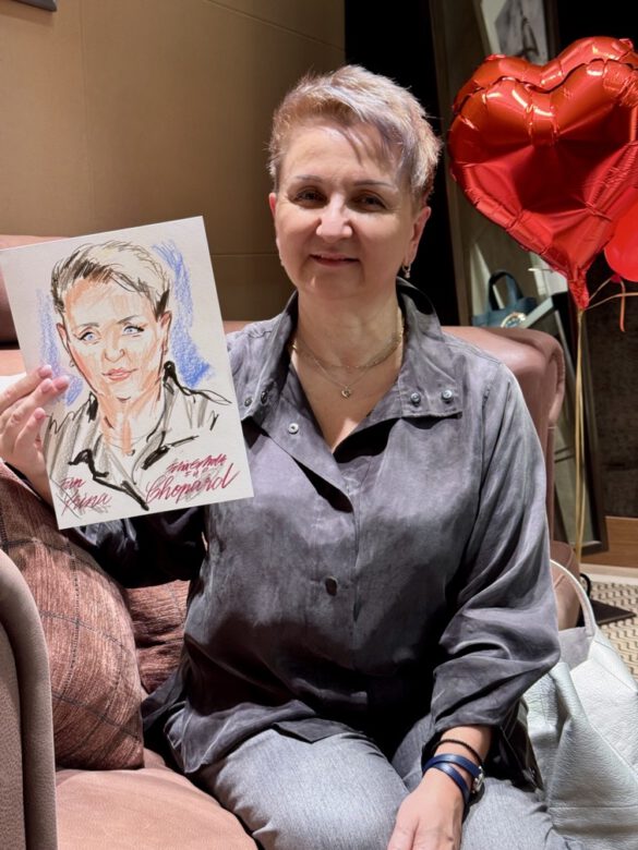 Felix Scholz_Live Event Illustration_Chopard Berlin Kurfürstendamm_24 Eine Dame mit kurzen blonden Haaren hält eine farbige Portraitzeichnung des Berliner Künstlers Felix Scholz