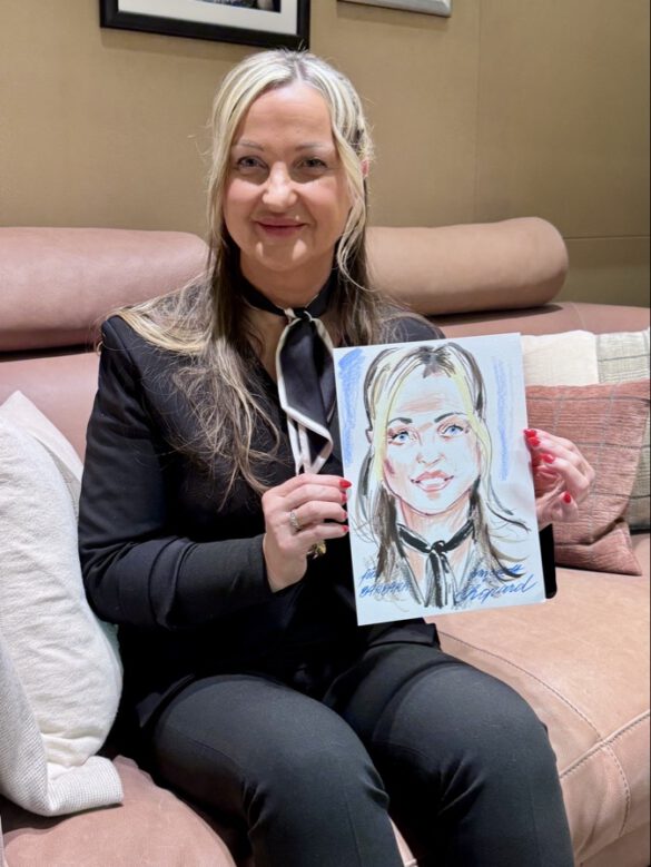 Felix Scholz_Live Event Illustration_Chopard Berlin Kurfürstendamm_5 Eine Dame in schwarzem Hosenanzug hält eine farbige Portraitzeichnung des Berliner Künstlers Felix Scholz