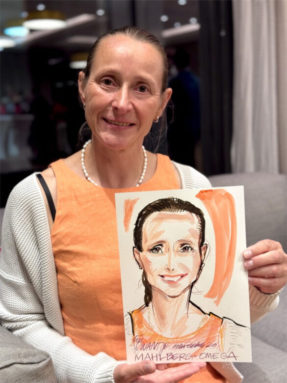 Eine Teilnehmerin der Juwelier Mahlberg + Omega Veranstaltung zeigt ihr handgezeichnetes Portrait, das Felix Scholz während des Events im Hotel Kieler Kaufmann als Live-Illustration angefertigt hat.